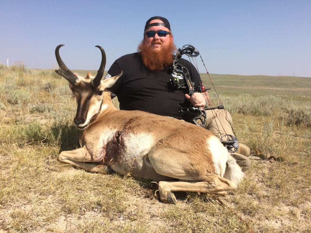 A man with a red beard next to his trophy antelope after an archery antelope hunt.