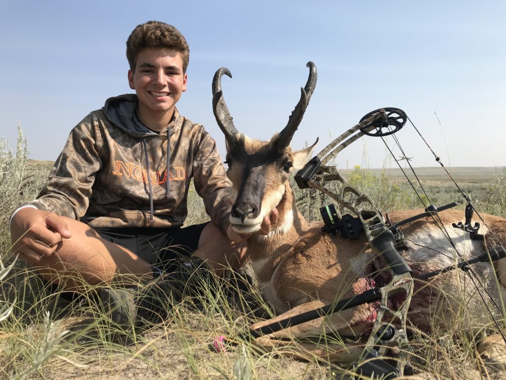 Teenage boy sitting next to his trophy antelope after a guided archery antelope hunt with Table Mountain Outfitters.