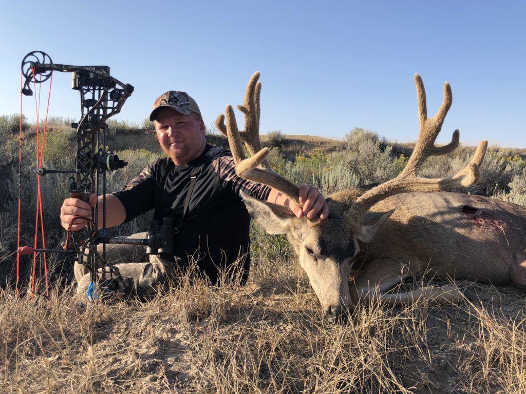 A man holding his trophy after an archery mule deer hunt with Table Mountain Outfitters